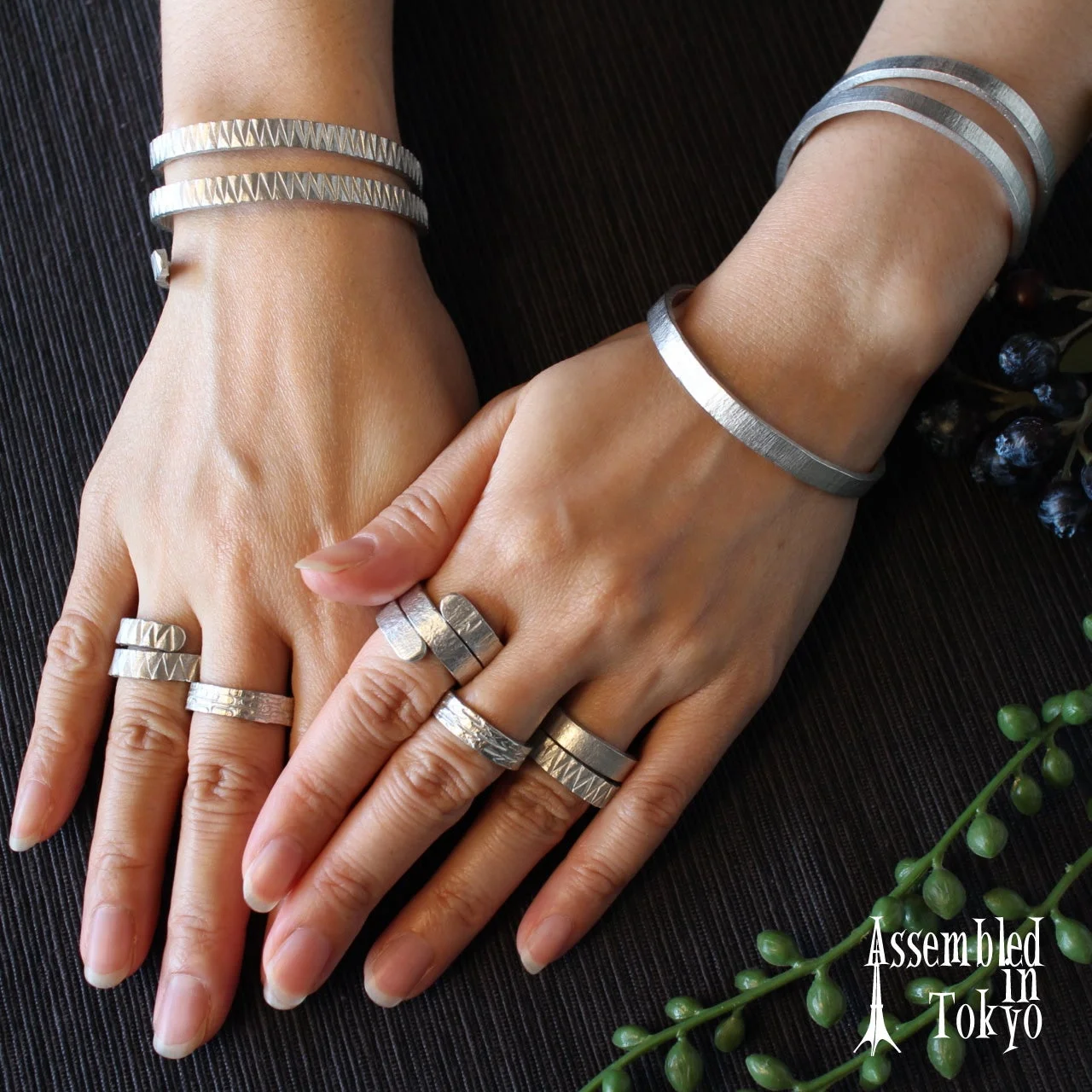 複数のシルバーカラーのバングルとリングを身につけた手元