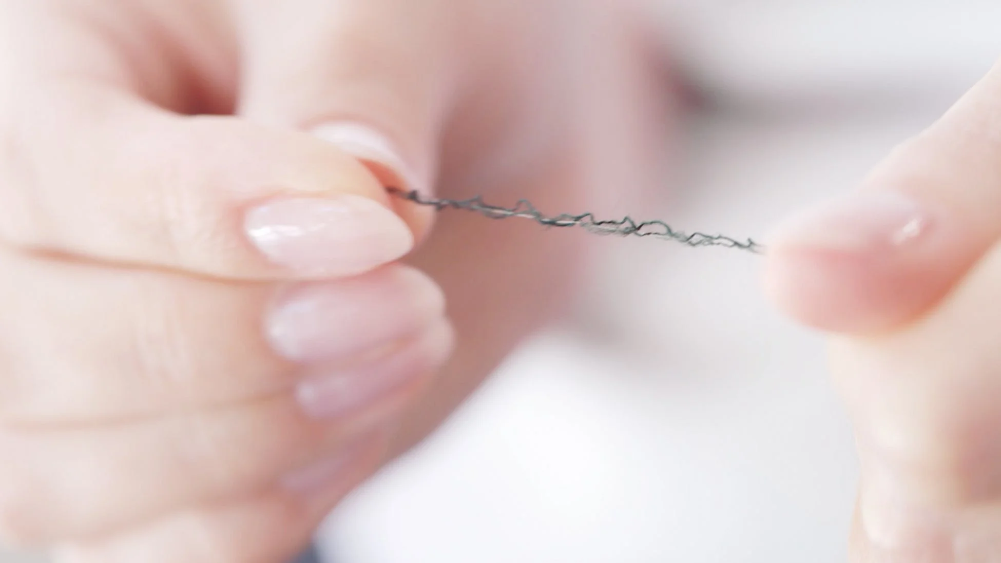 指で細い糸をつまむ様子