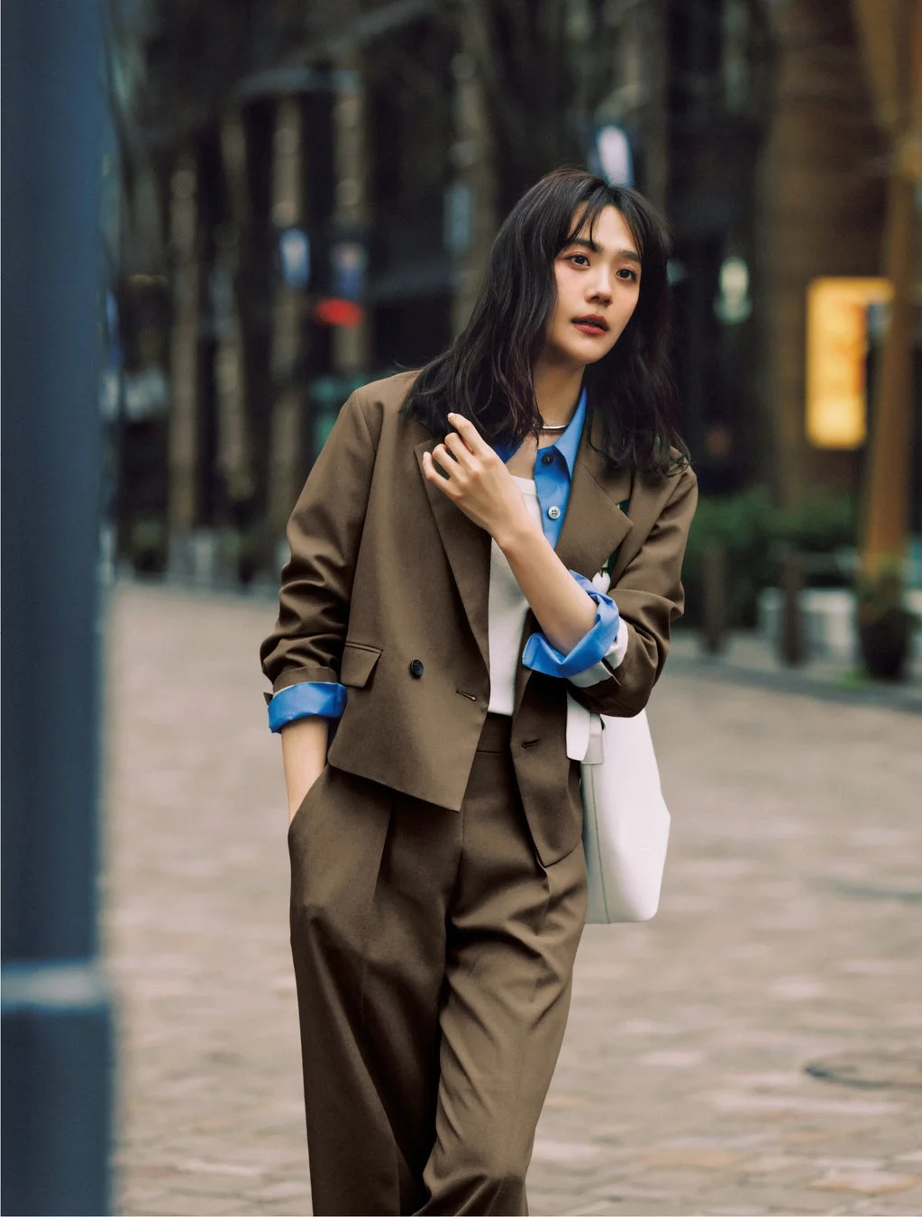 茶色のスーツと青いシャツを着用した女性