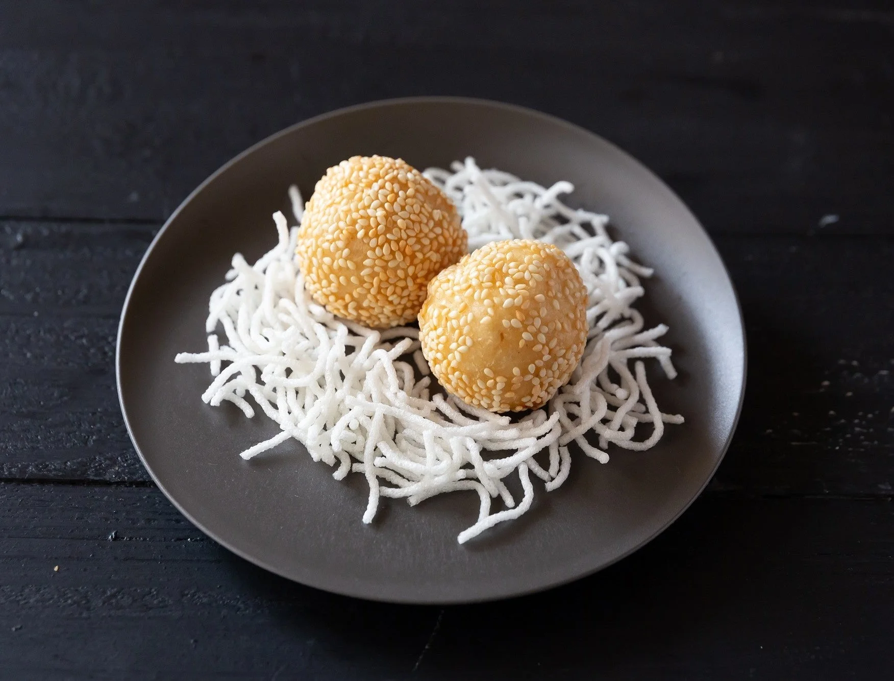黒い皿に盛られた2つのごま団子