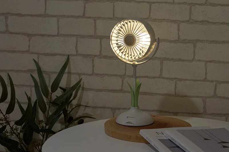 レンガの壁を背景に、LEDライト付きのユニークなデザインのテーブルランプが置かれた室内風景。木製のコースターと本が添えられ、落ち着いた雰囲気を醸し出しています。