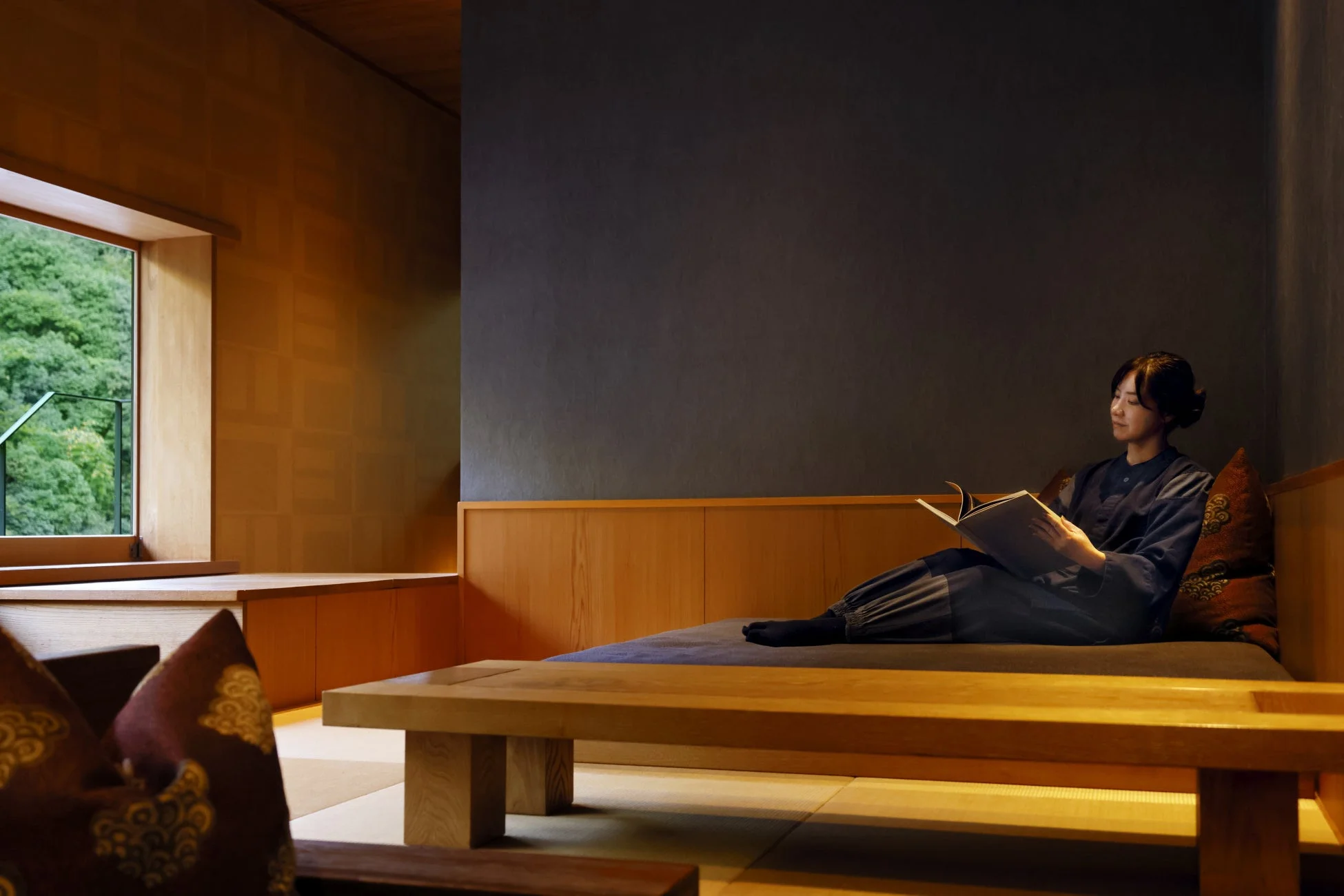 窓から豊かな緑を望む和風空間で読書を楽しむ女性