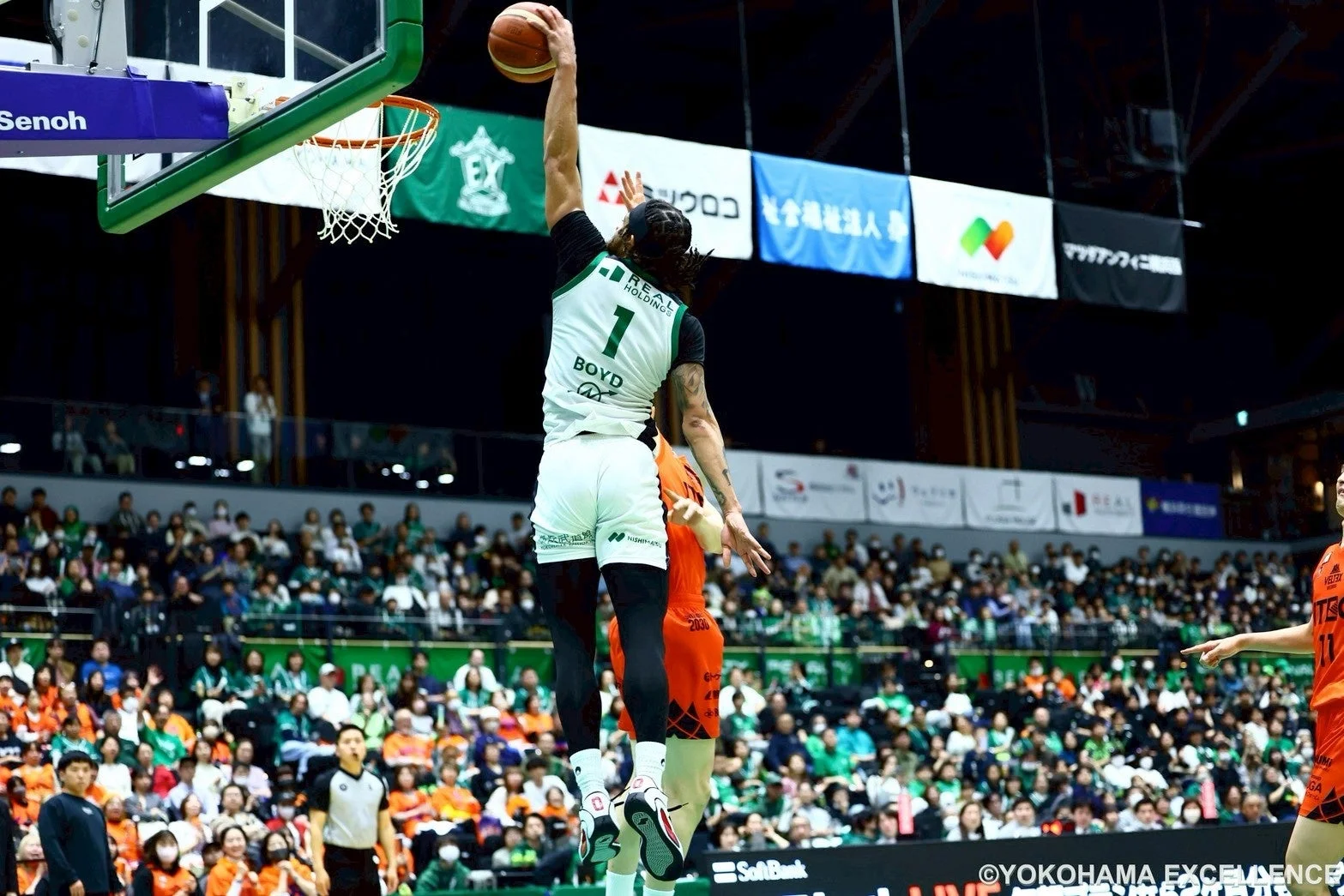 バスケットボールの試合で、背番号1の選手が豪快なダンクシュートを決めている瞬間を捉えています。観客で賑わうアリーナの熱気が伝わる一枚です。