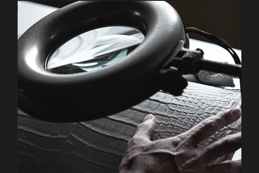 拡大鏡で革を検査する職人