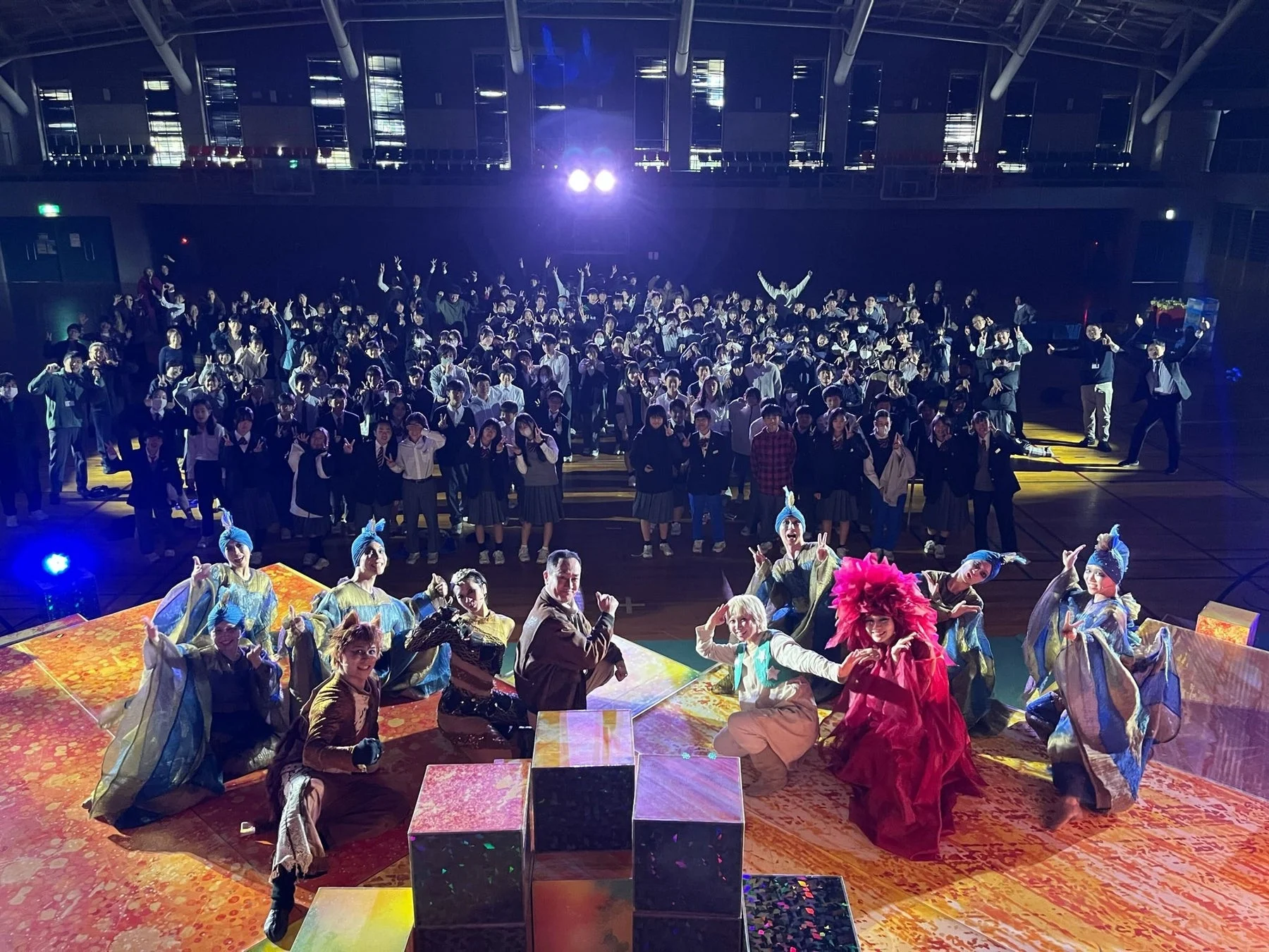 学校の体育館でパフォーマンスをする役者たちと観客