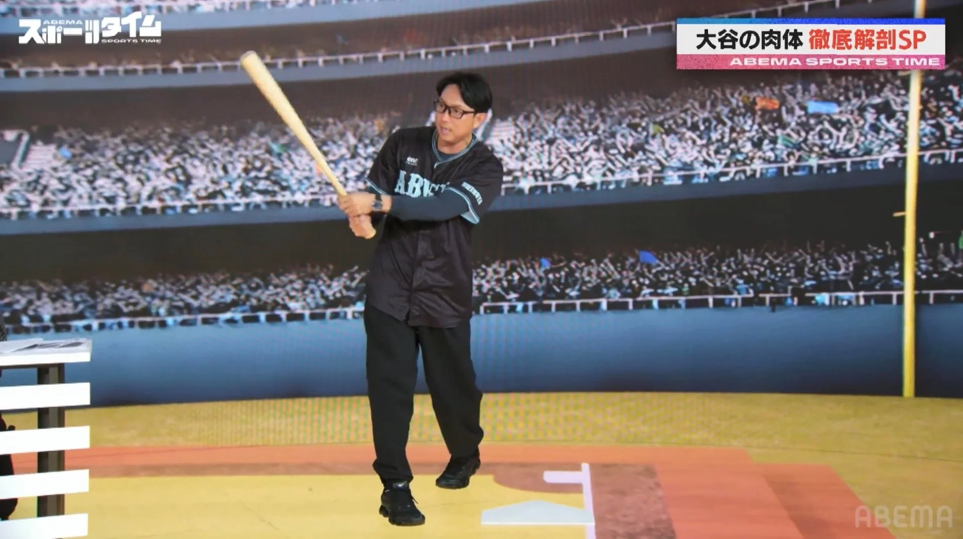 野球のユニフォームを着た男性がバットを構え、野球場を背景にしている画像