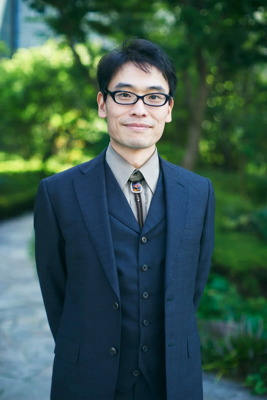 緑豊かな屋外を背景に撮影された男性のポートレート