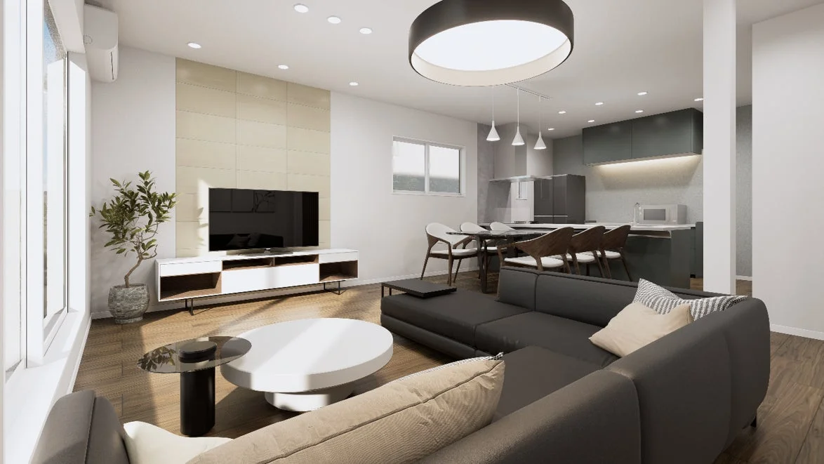 モダンで広々としたリビングダイニングキッチン（LDK）の室内風景です。ダークグレーのL字型ソファと白いコーヒーテーブルが配置され、奥にはテレビと観葉植物があります。ダイニングエリアには木製の椅子とテーブルがあり、その奥にはスタイリッシュなオープンキッチンが広がっています。全体的に明るく洗練された空間です。