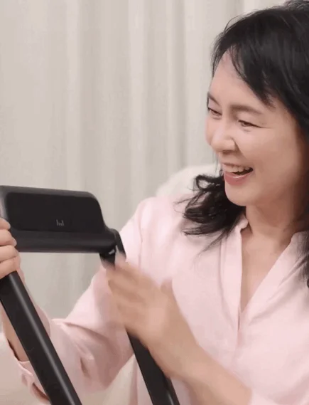 ピンクのシャツを着た女性が笑顔で黒いデバイスを操作