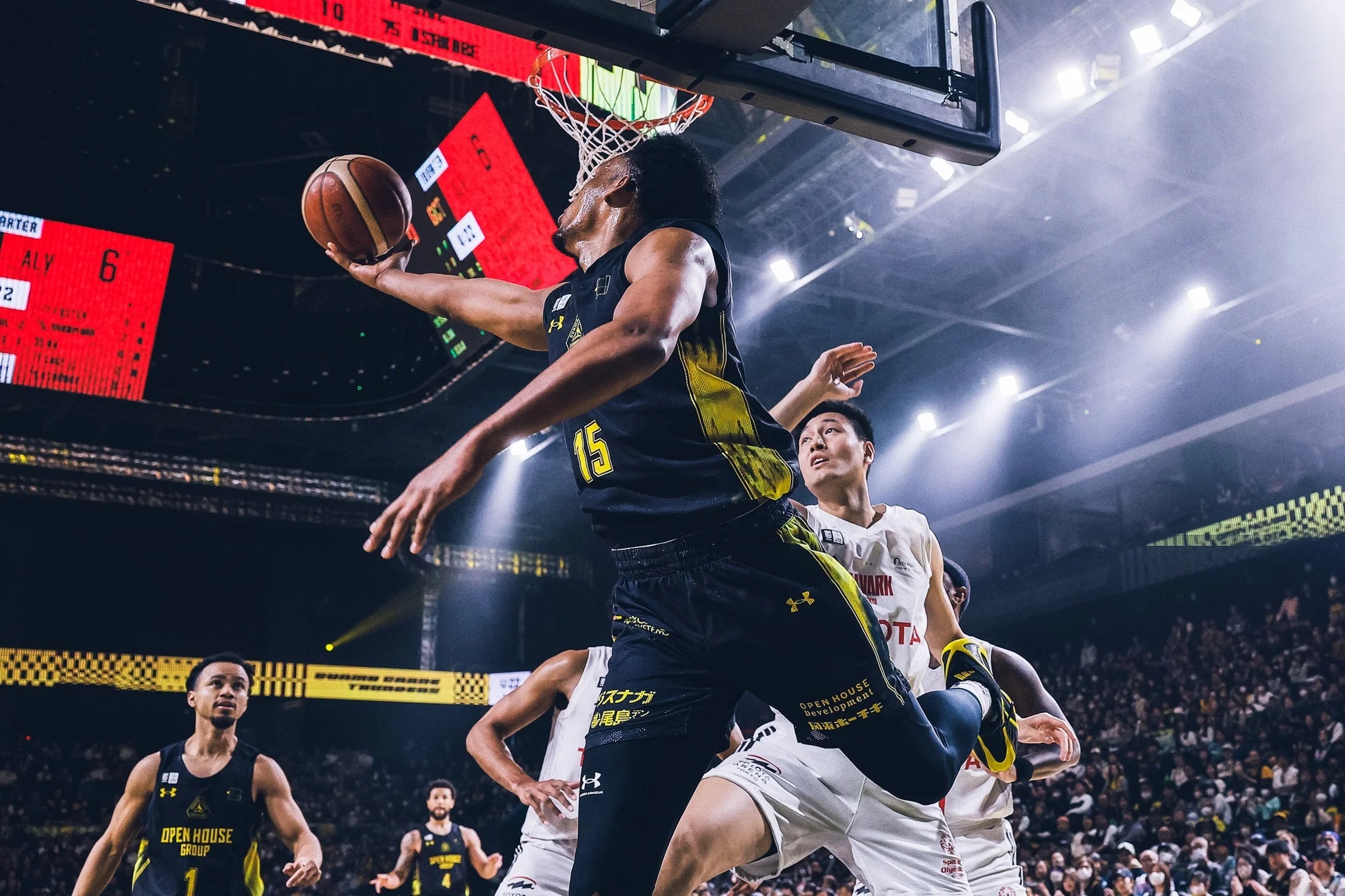 バスケットボールの試合中、ゴールに向かって高く跳び上がりシュートを試みる選手