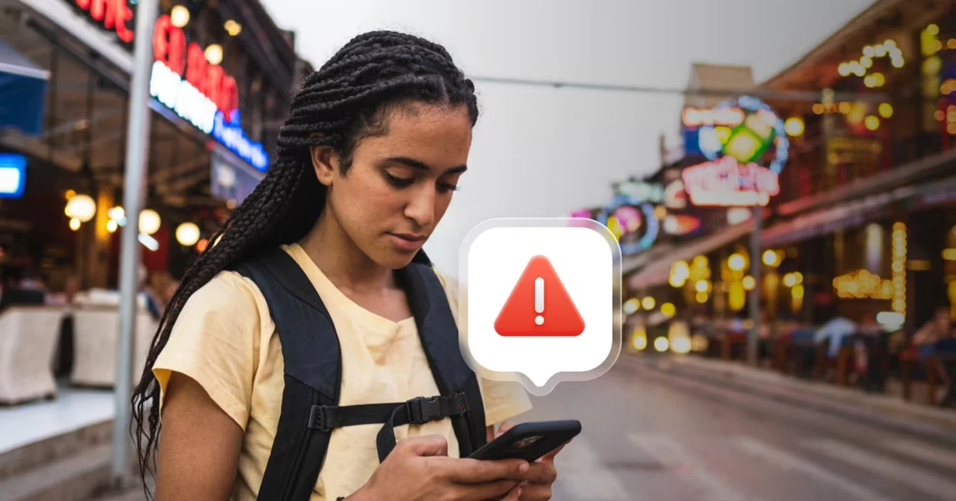 スマートフォンを操作する女性の画面に警告マーク