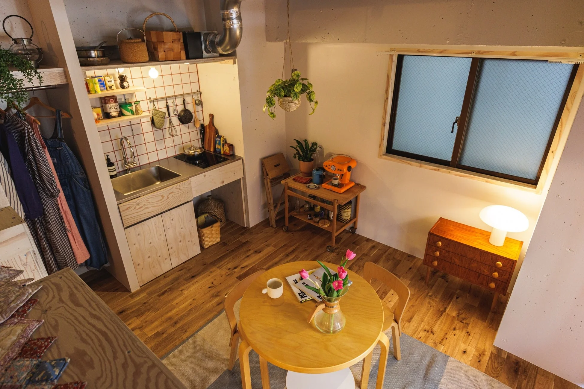 キッチン、ダイニング、カフェコーナーが一体となった、木製家具と植物が配された居心地の良い生活空間です。