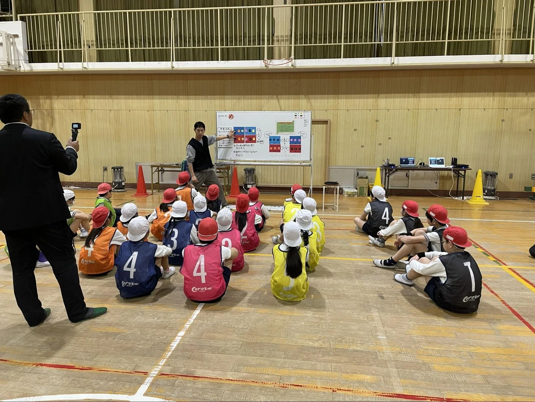 体育館で講師の説明を聞く子どもたち