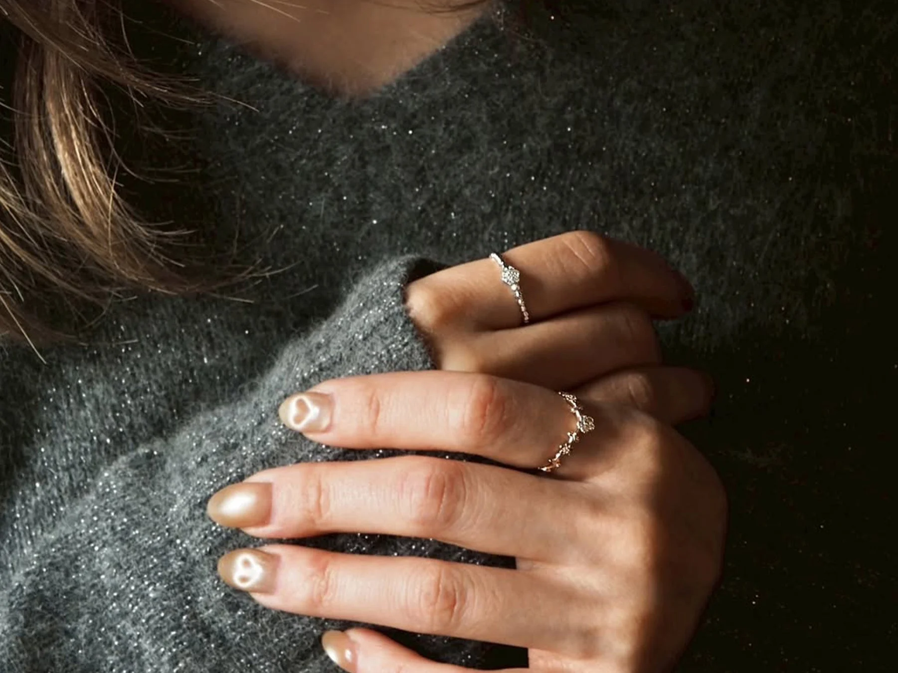 煌めくグレーのセーターを着用した人物の手元を捉えた画像