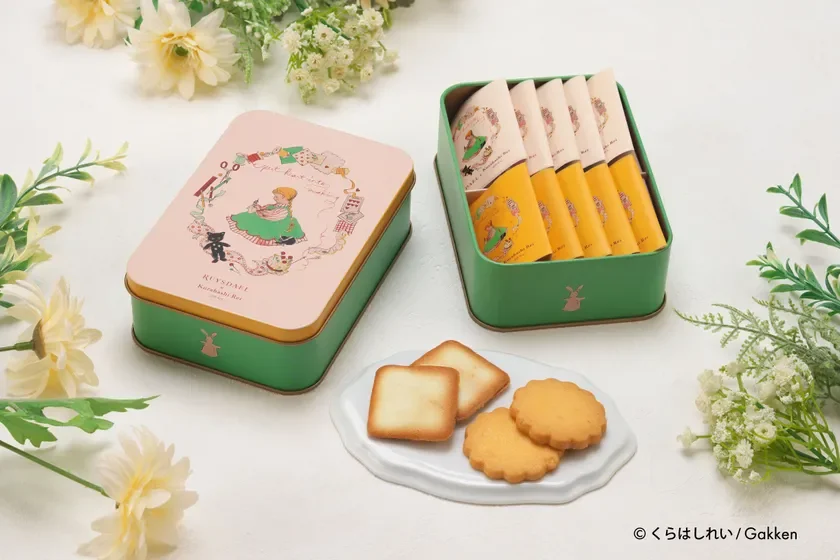 可愛らしいイラストが描かれたピンクとグリーンの缶入りクッキーと、お皿に盛られたクッキー