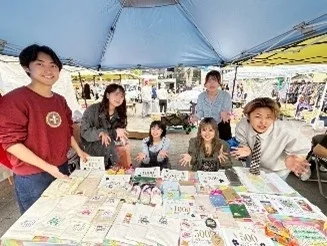 屋外マーケットで商品を販売する学生たち