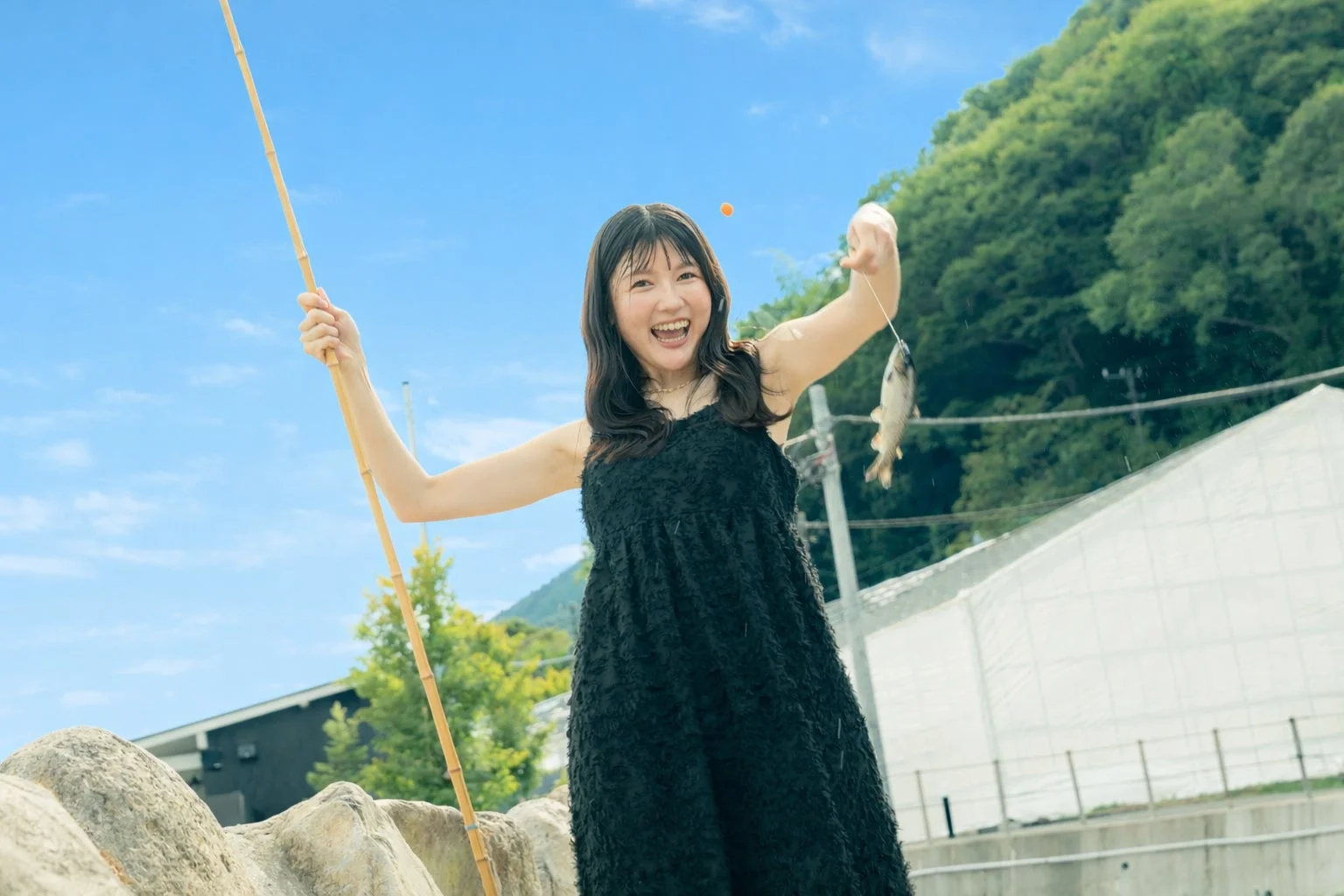 満面の笑みを浮かべた女性が魚を釣っている