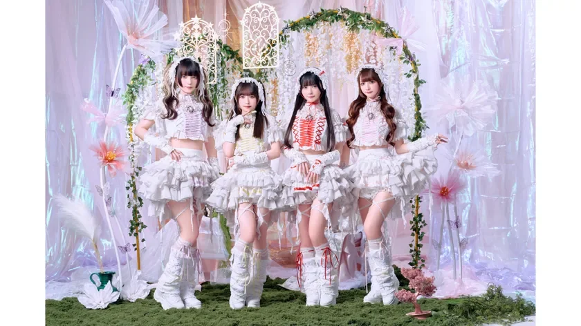 フリルの白い衣装をまとった4人の女性アイドルグループ