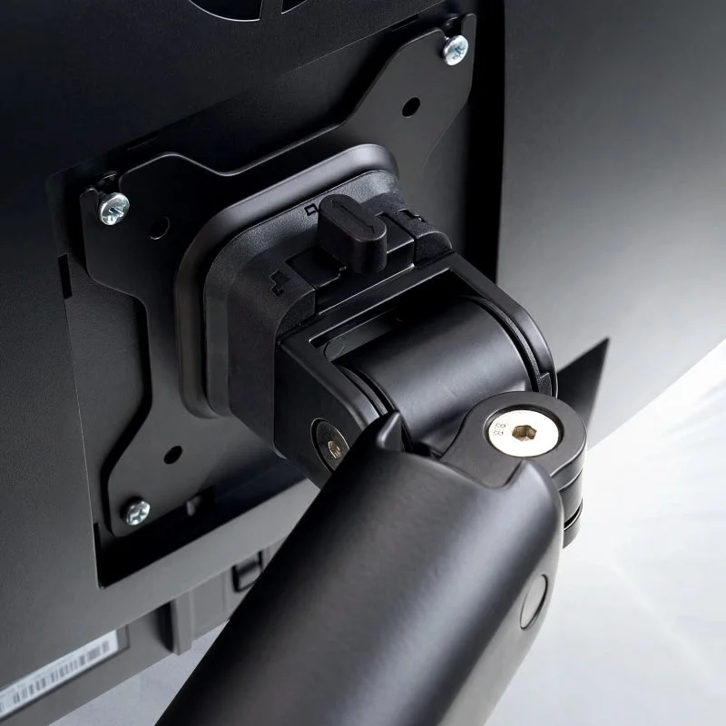 モニターの背面にあるVESAマウントと、それに接続されたモニターアームの接合部をクローズアップした画像です。黒い部品が中心で、ネジでしっかりと固定されています。