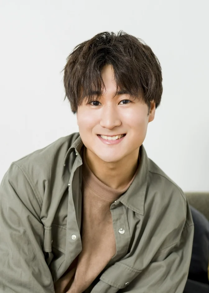 白い背景の前で笑顔を見せる若い男性