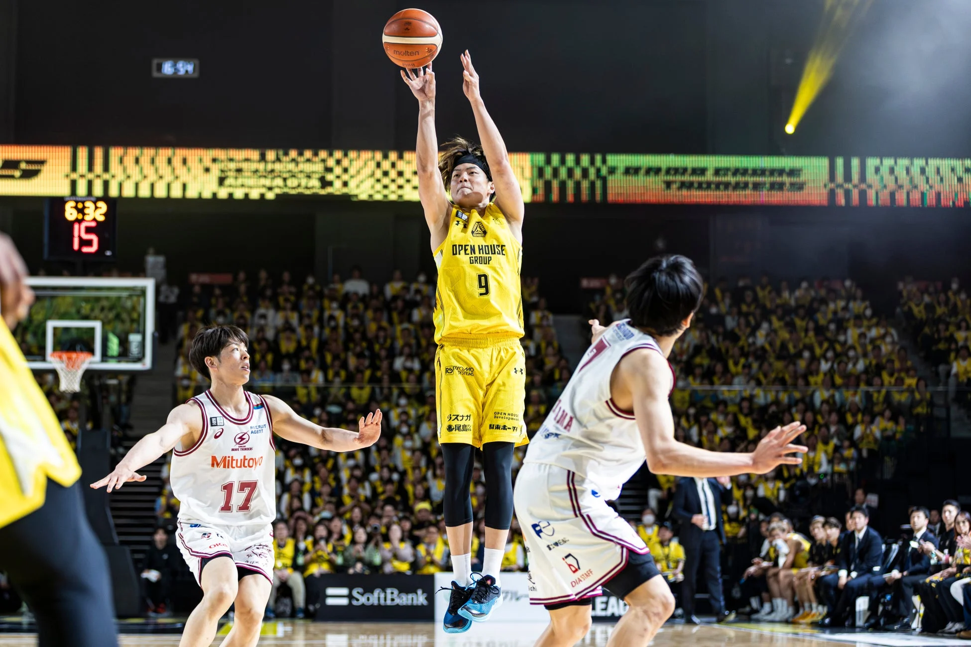 バスケットボールの試合中、黄色いユニフォームを着た選手がジャンプしてシュートを放っている瞬間