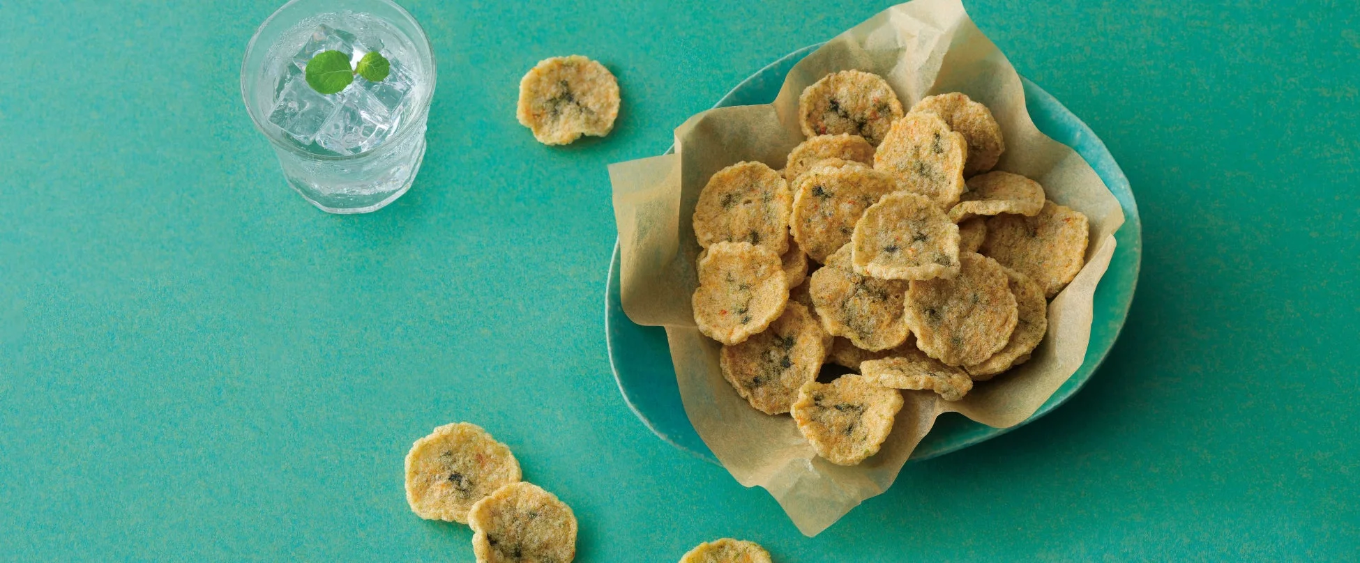 丸くて平たいスナック菓子が盛られた皿とミント水