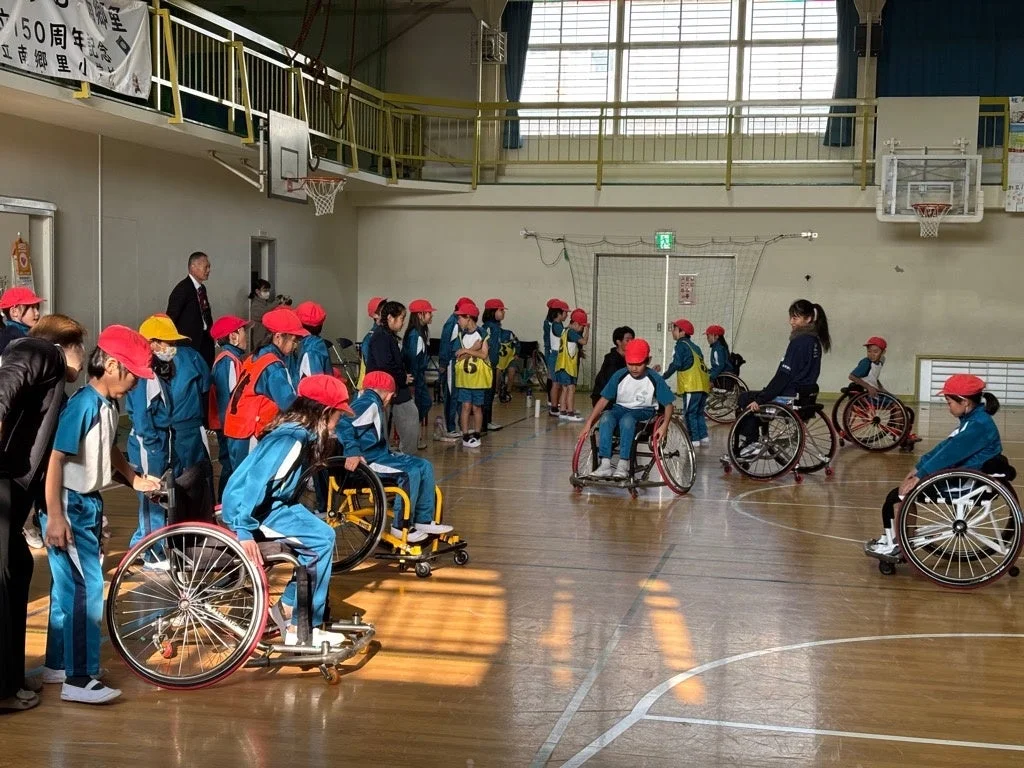 体育館でスポーツ用車いすに乗って活動する小学生たち