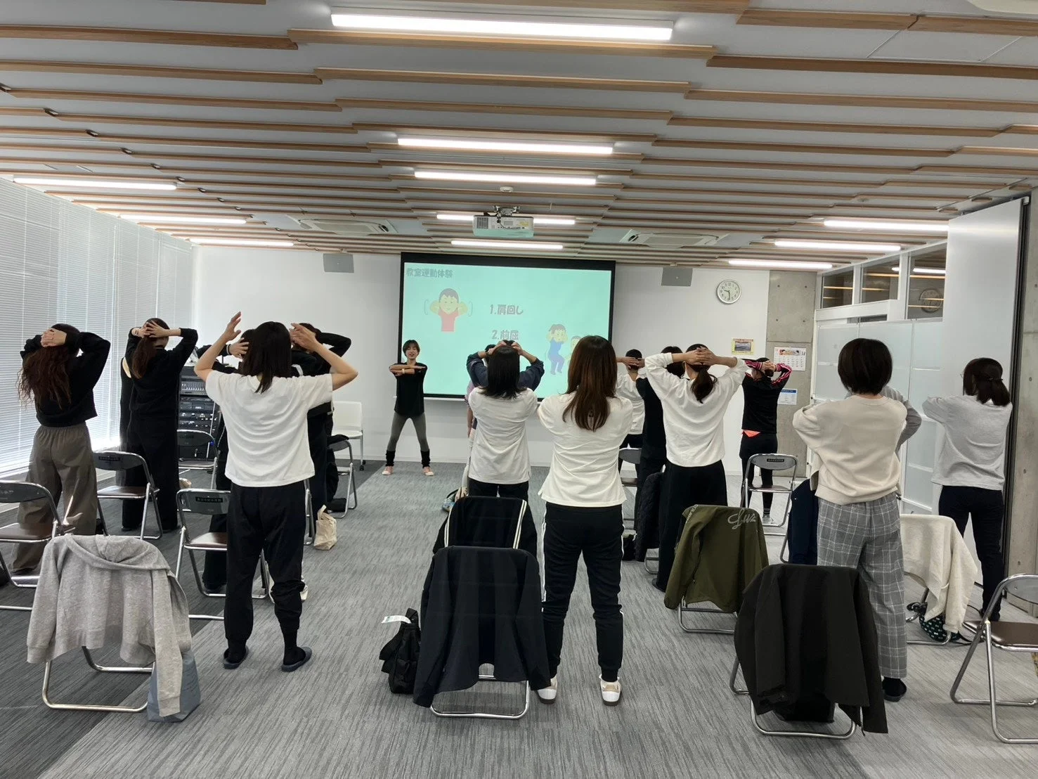 オフィスのような部屋で健康運動をする人々