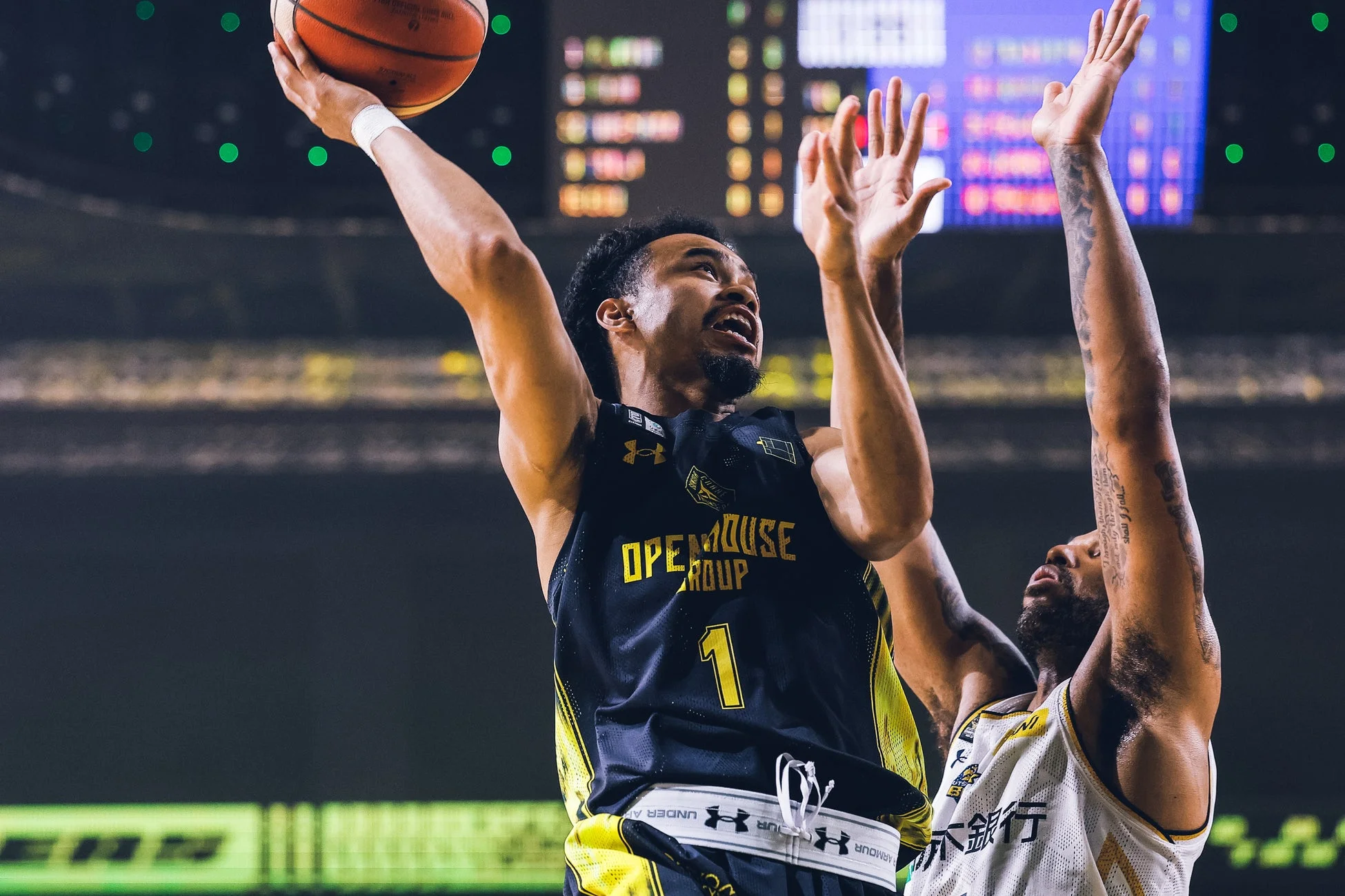 バスケットボールの試合で、黒と黄色のユニフォームを着た選手がシュートを放つ瞬間