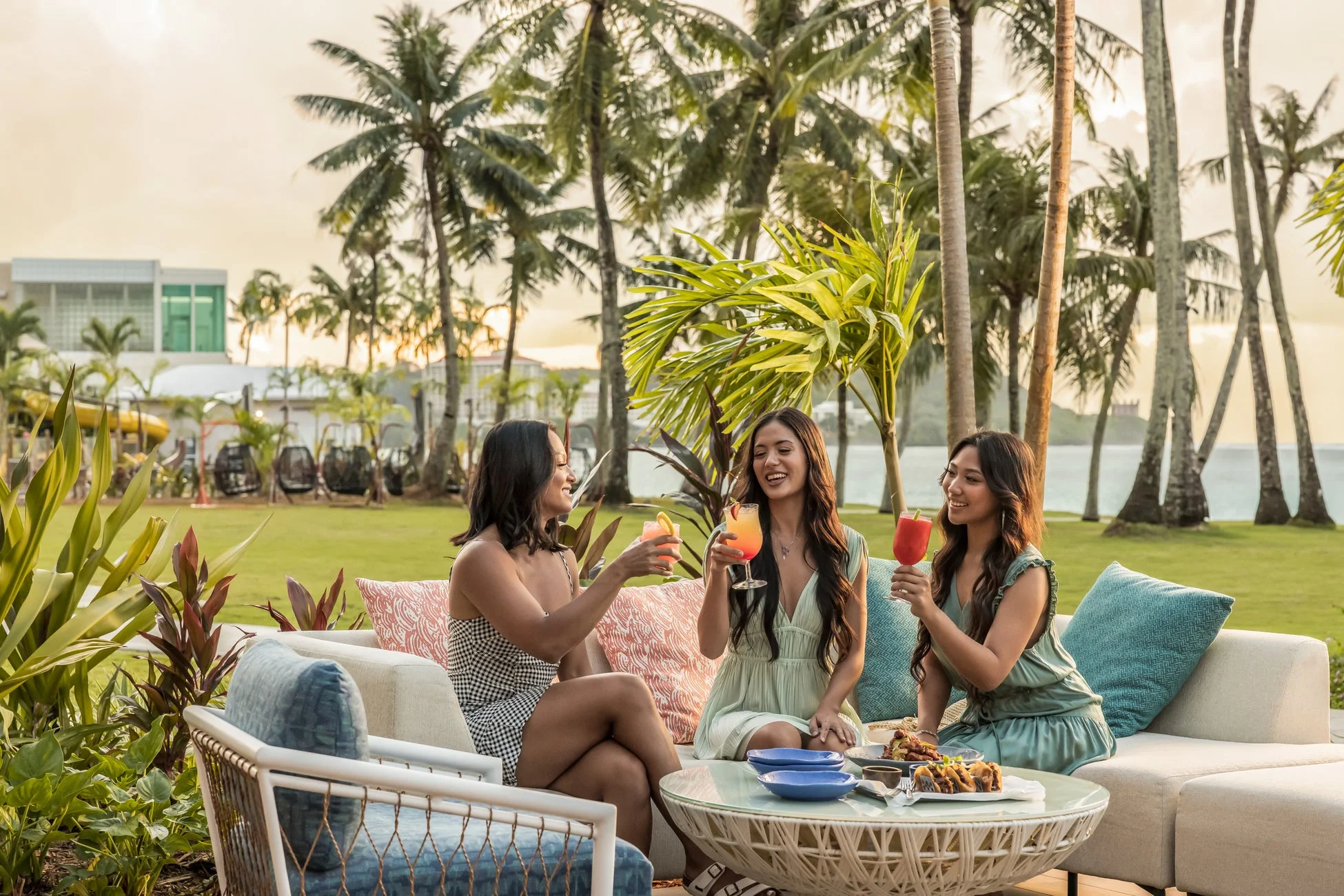 夕暮れ時のトロピカルな屋外で、カクテルを楽しむ女性たち