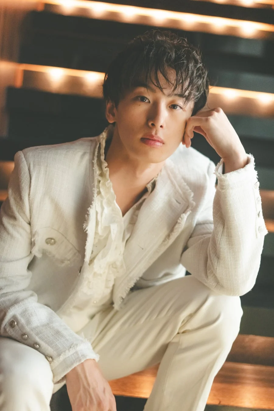 白いスーツを着て真剣な眼差しでカメラを見つめる若い男性