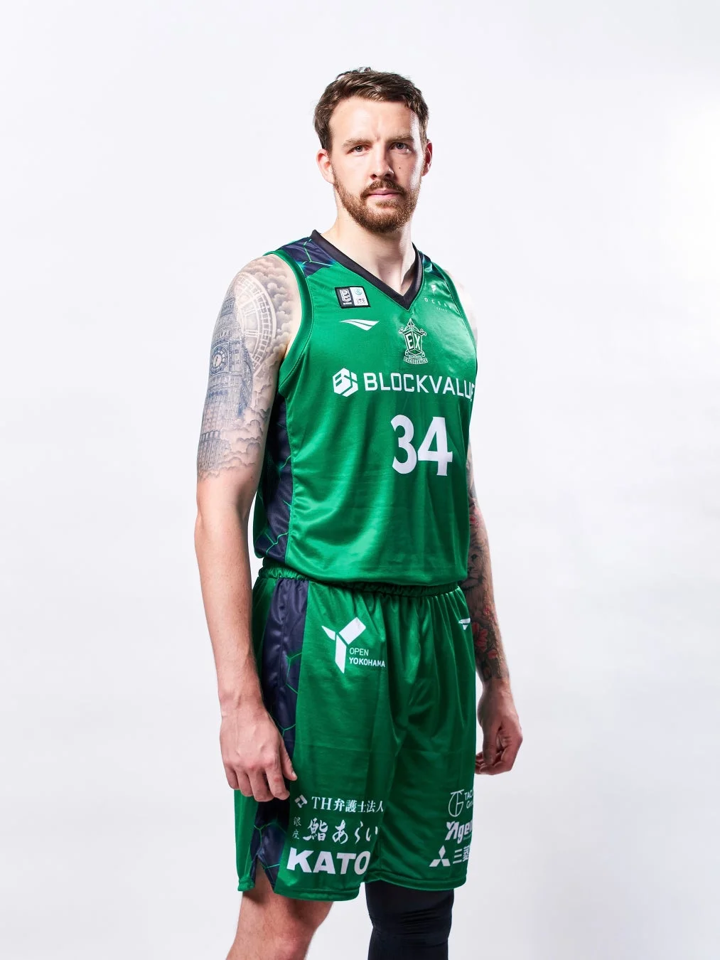 緑色のバスケットボールユニフォームを着た男性選手が白い背景の前でポーズをとっています。