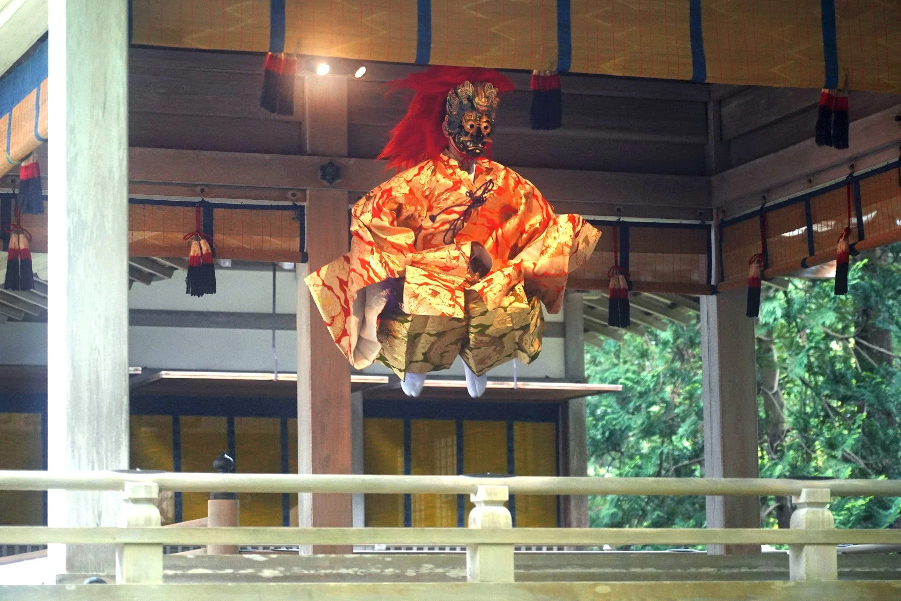 伝統的な木造建築内に吊るされた仮面と豪華な衣装の人形