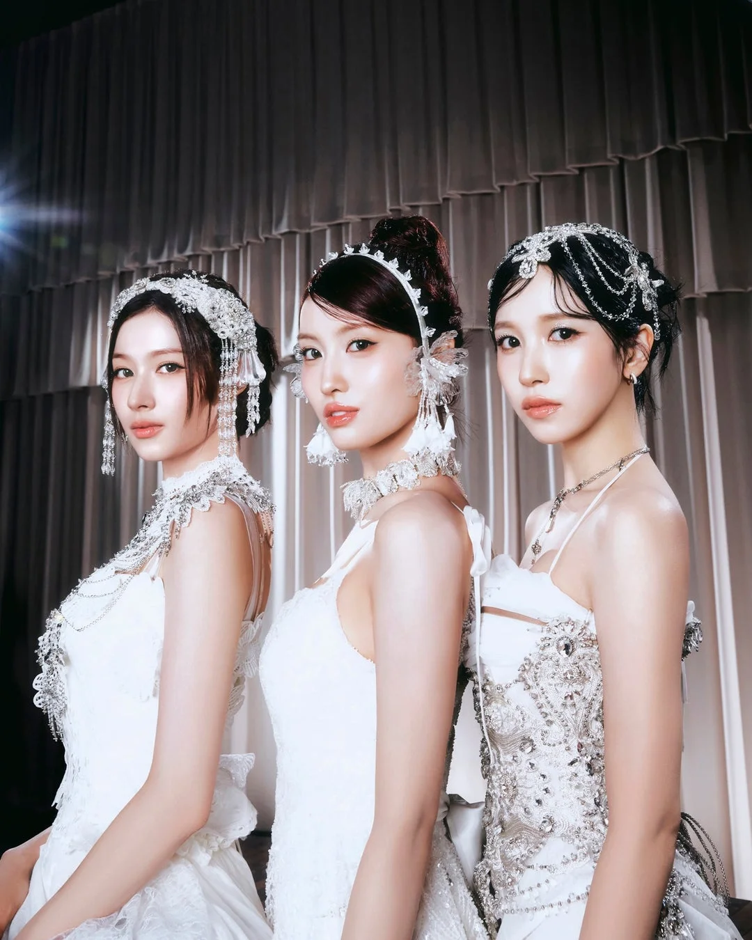 白い豪華なドレスと煌びやかなアクセサリーを身につけた3人の女性が並んでポーズをとっています。