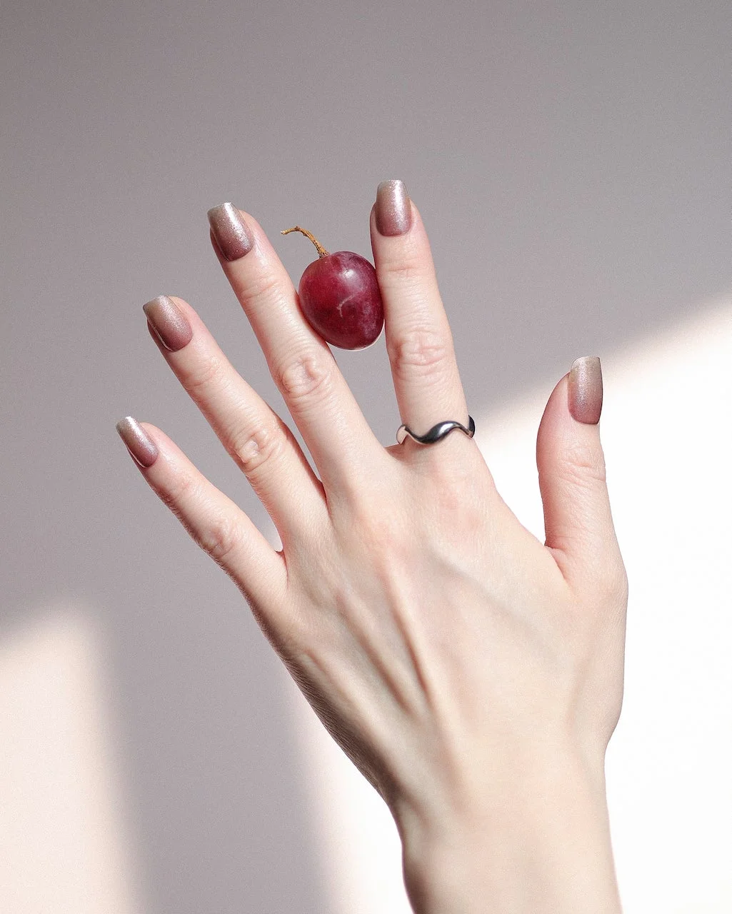 ぶどうを持つ手元のネイルアレンジ