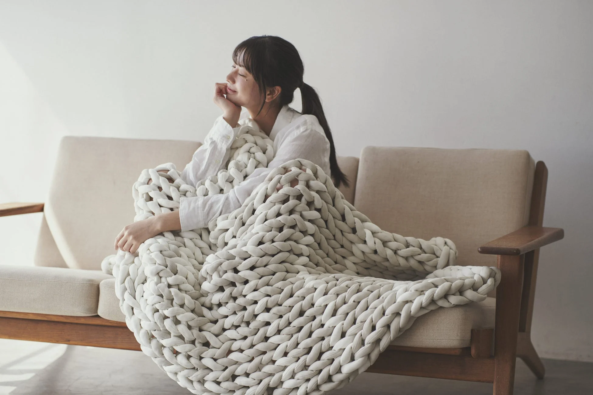 ソファでくつろぐ女性とブランケット