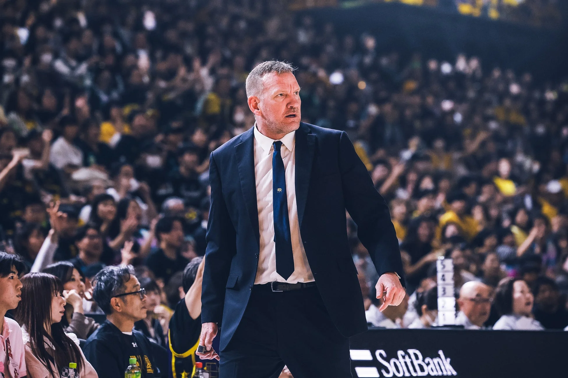 スポーツアリーナのサイドラインに立つ男性コーチ