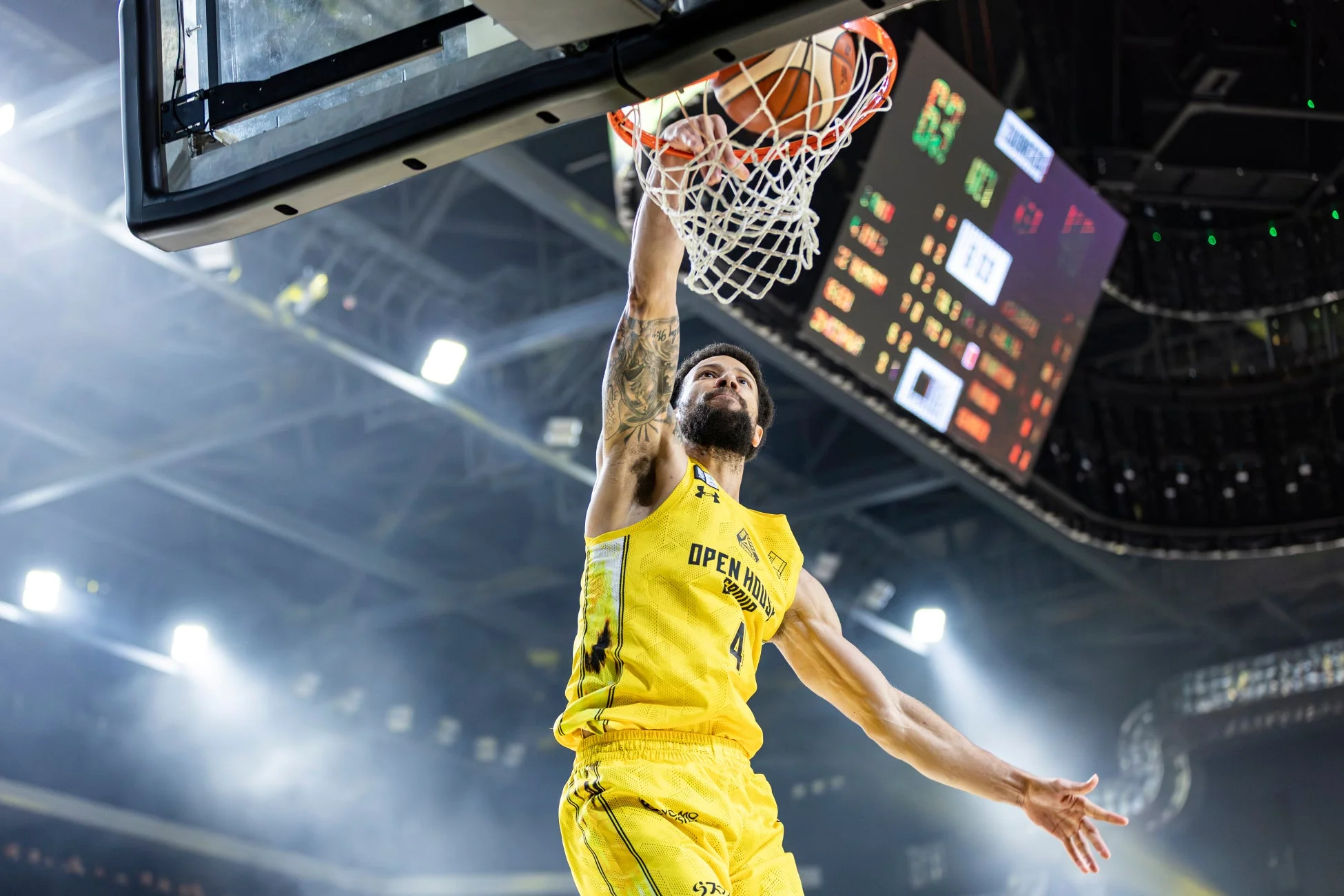 黄色いユニフォームを着たバスケットボール選手が、試合中に豪快なダンクシュートを決めている瞬間