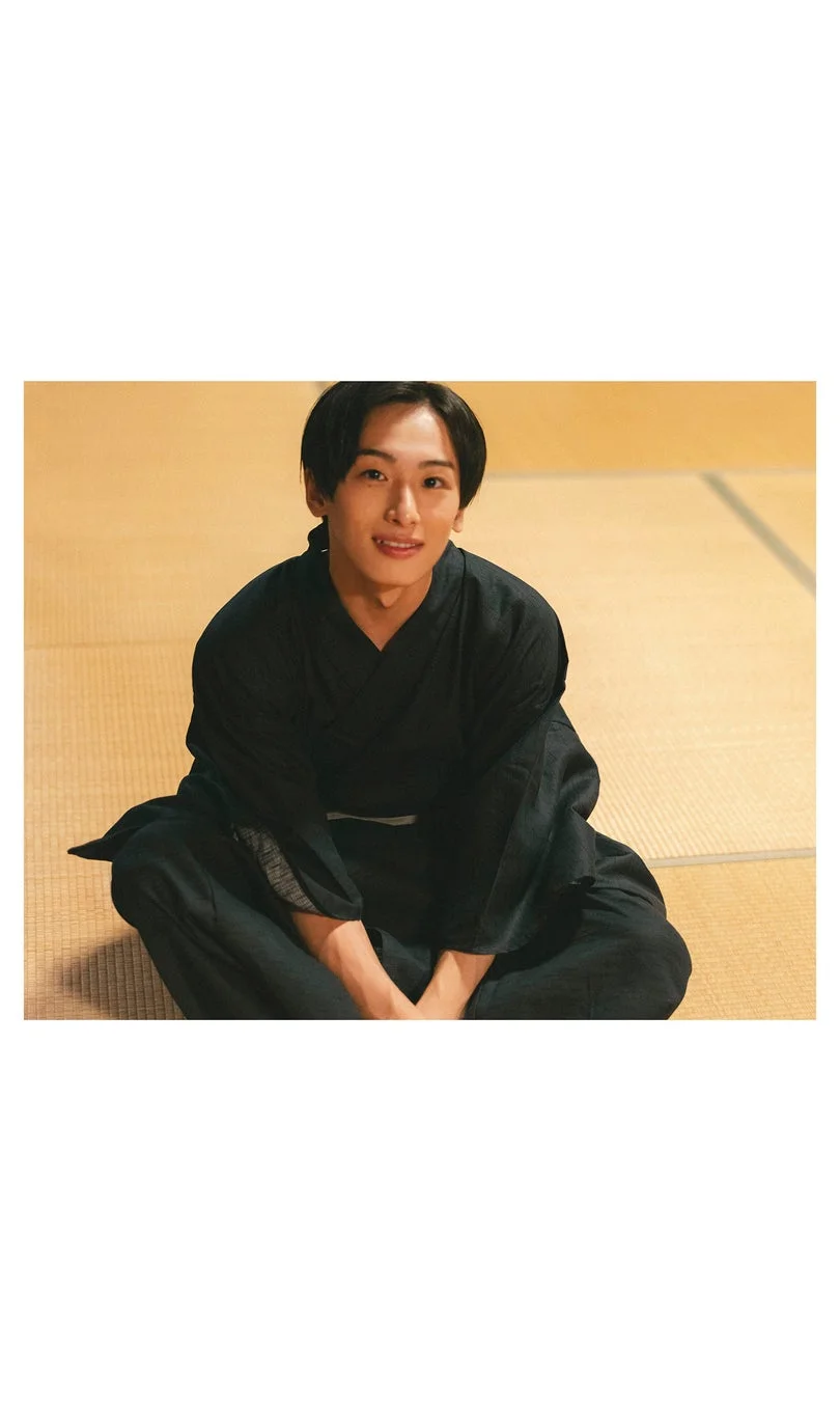 黒い着物を着て畳に座り笑顔を見せる若い男性