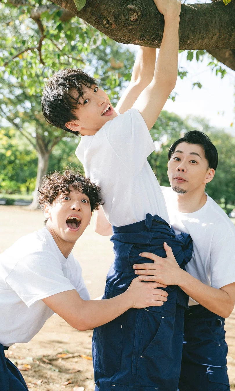 公園で木にぶら下がる仲間を支える3人の男性