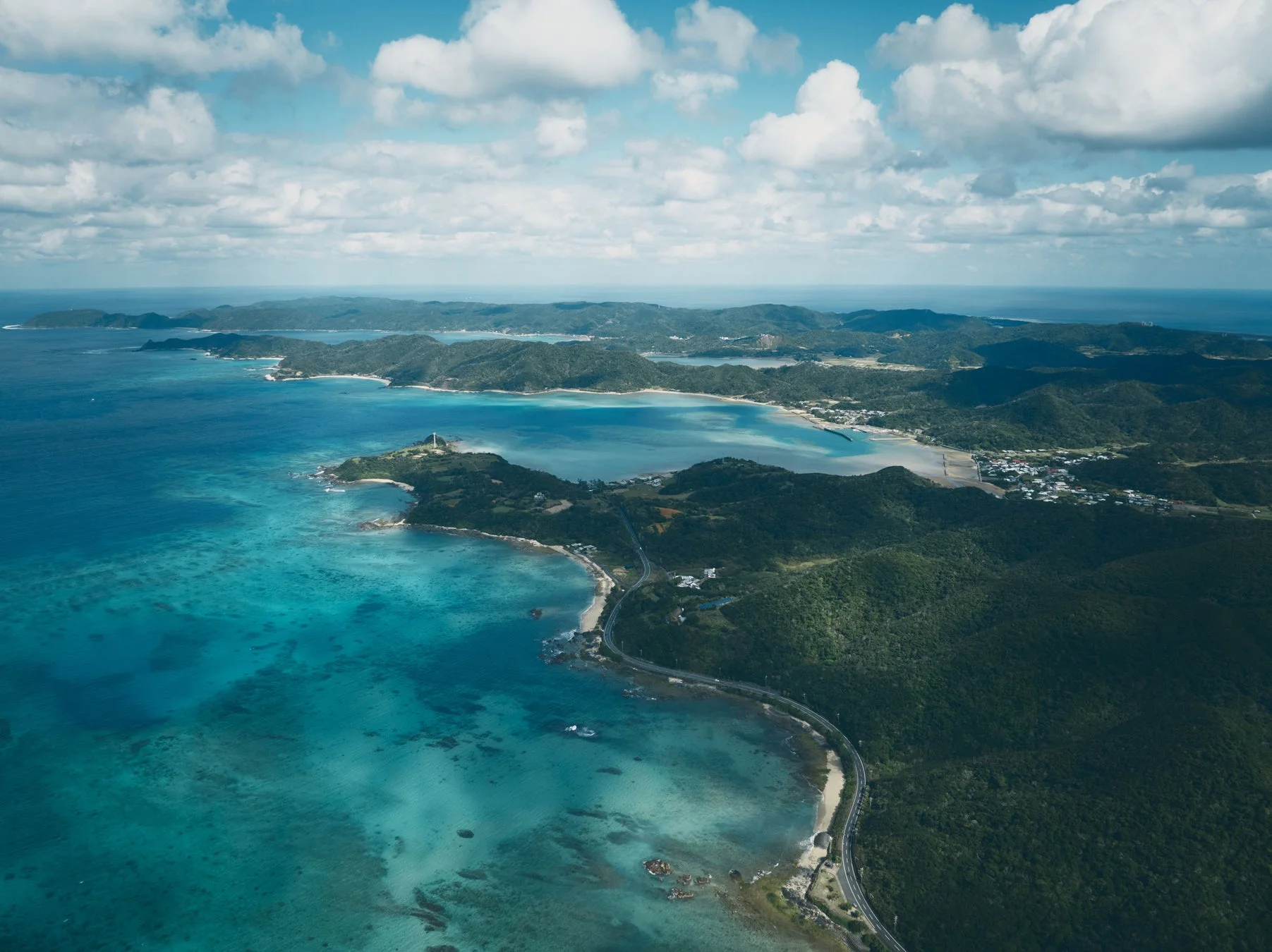 エメラルドグリーンの海と豊かな緑の島々が広がる海岸線の空撮