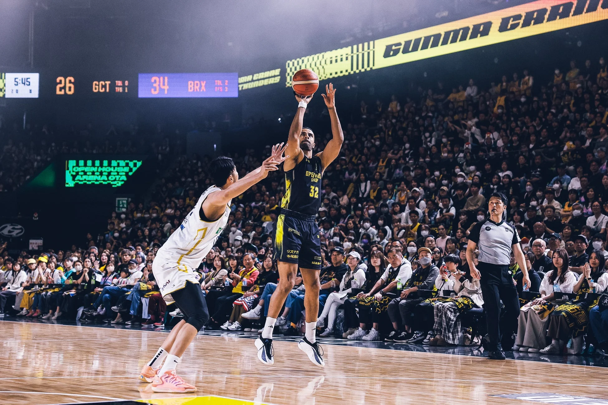 バスケットボールの試合中、選手が空中でボールをシュートしている瞬間