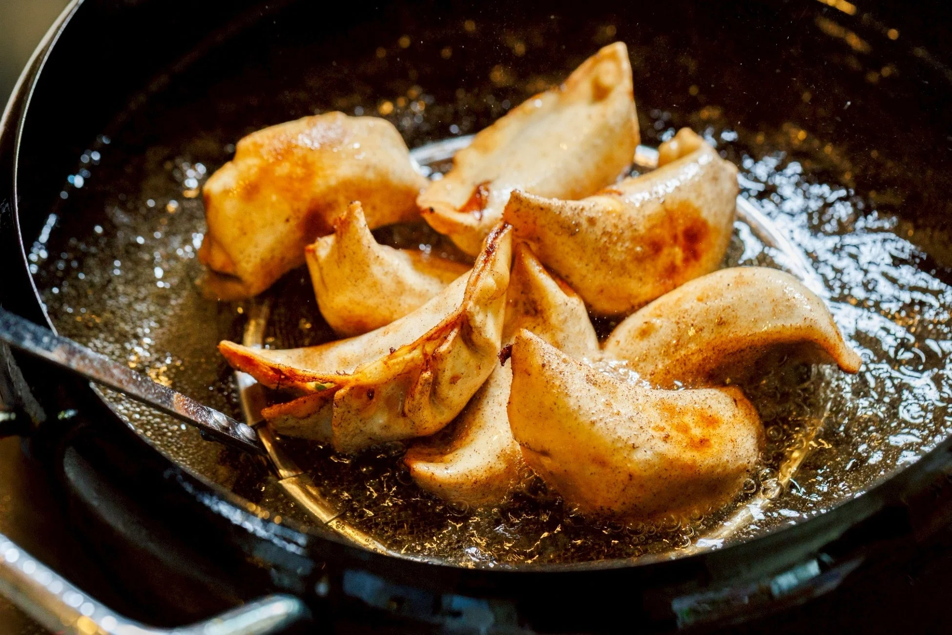 熱い油で揚げられている黄金色の餃子