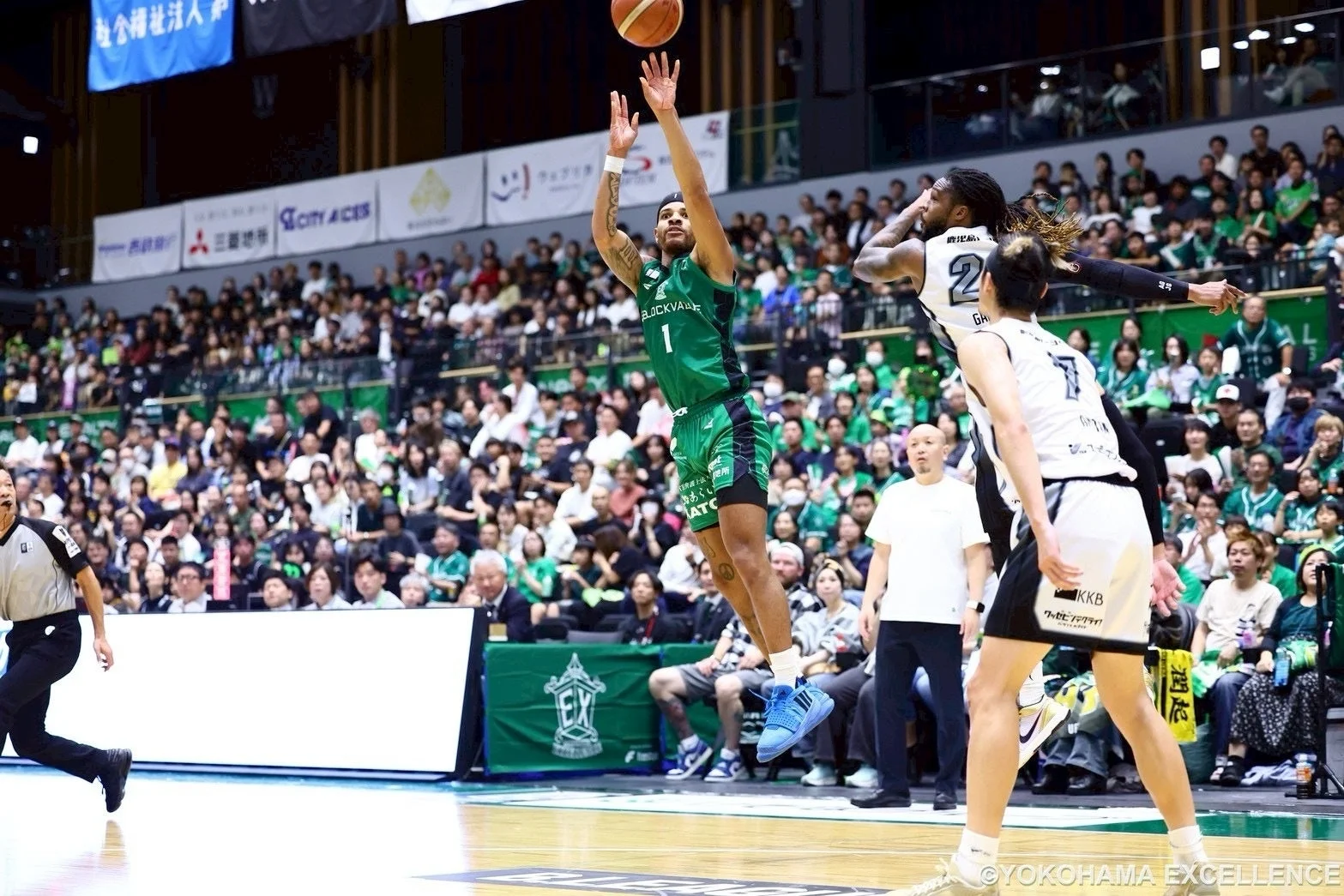 バスケットボールの試合中、緑のユニフォームを着た選手がシュートを放つ瞬間を捉えた写真