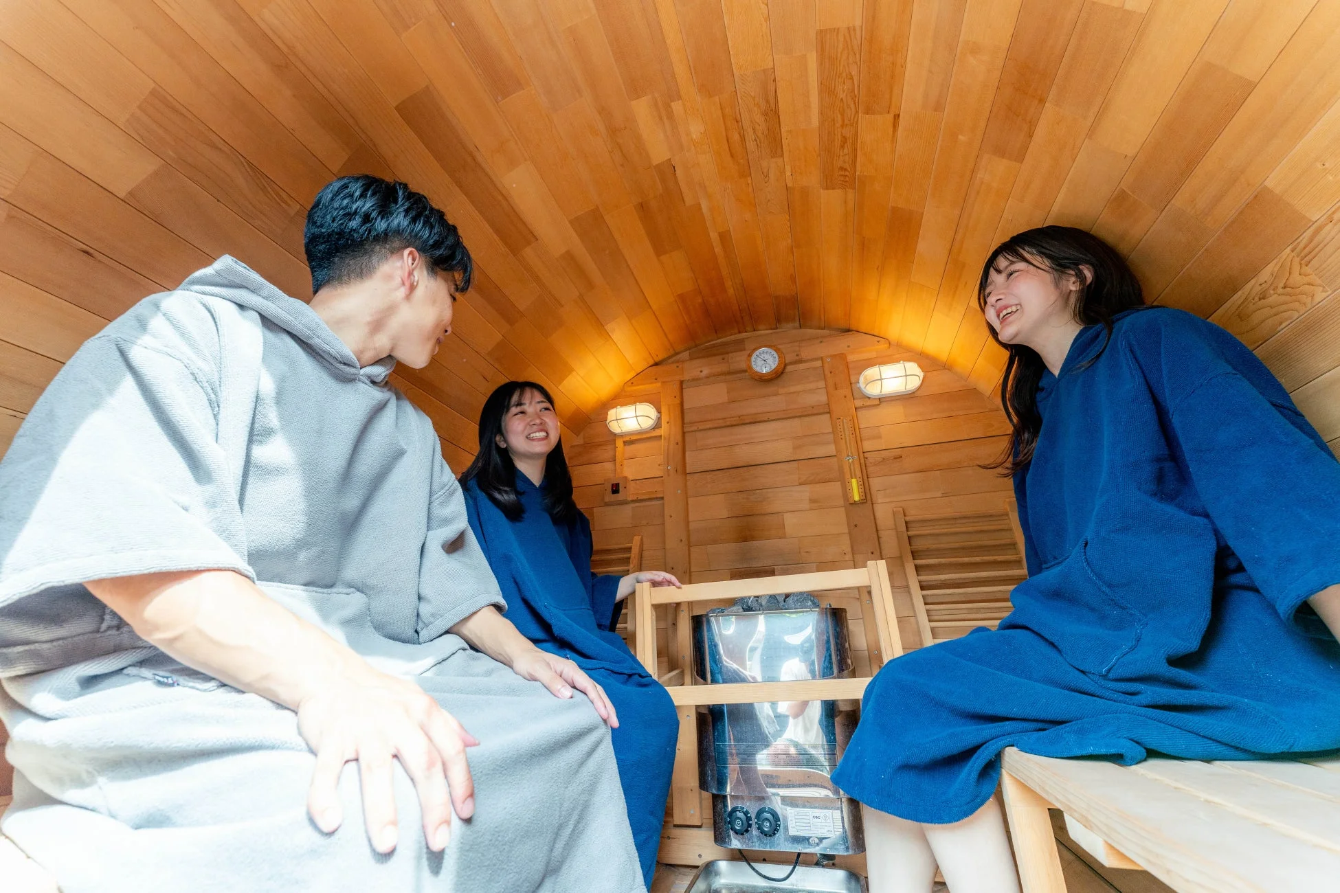 木製のバレルサウナでリラックスした様子で談笑する友人たち