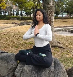 公園の岩の上で瞑想ポーズをとる女性
