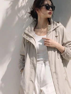 ベージュのフード付きコートとサングラスの女性