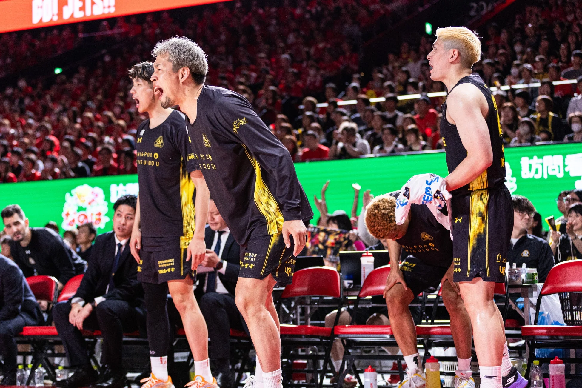 バスケットボールの試合中、ベンチにいる選手たちが熱心に声援を送っている様子