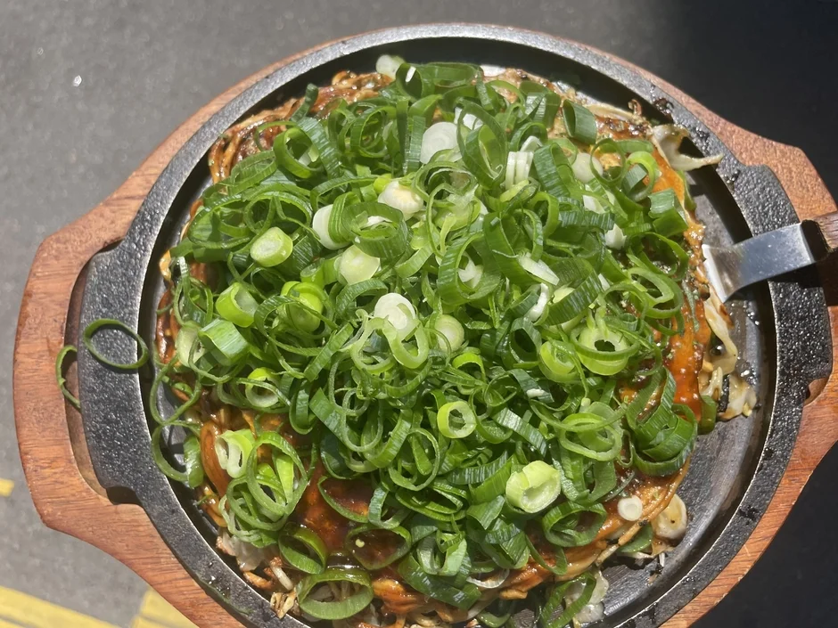 鉄板に乗ったネギたっぷりの焼き料理。