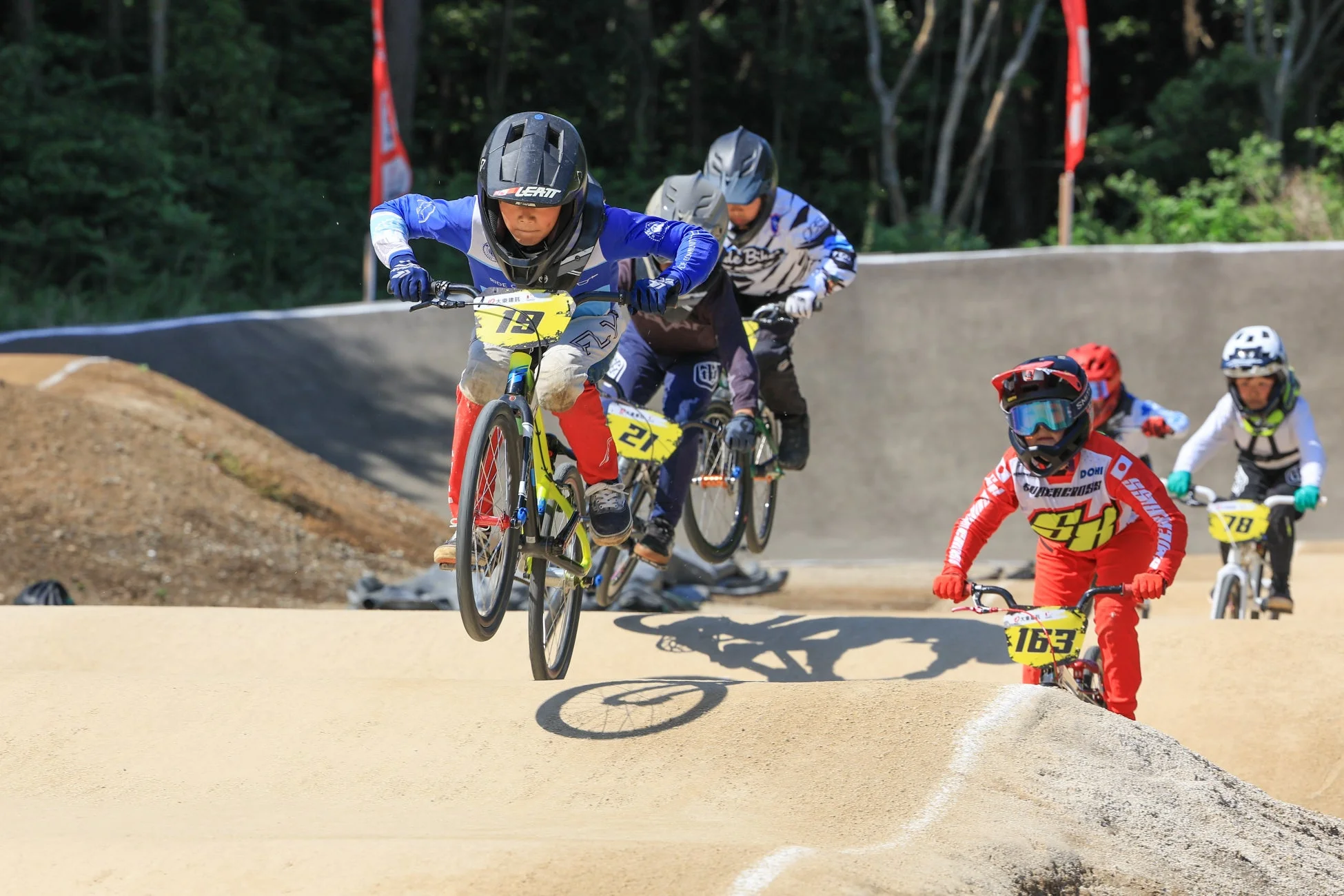 BMXレースの競技中にジャンプする複数の若いライダーたち
